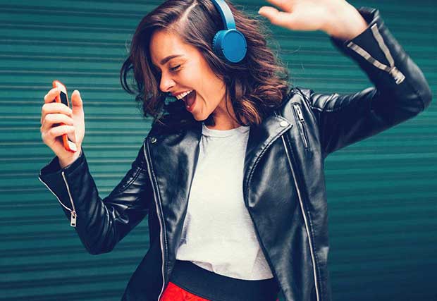 Woman dancing and listening to music with bluetooth headphones